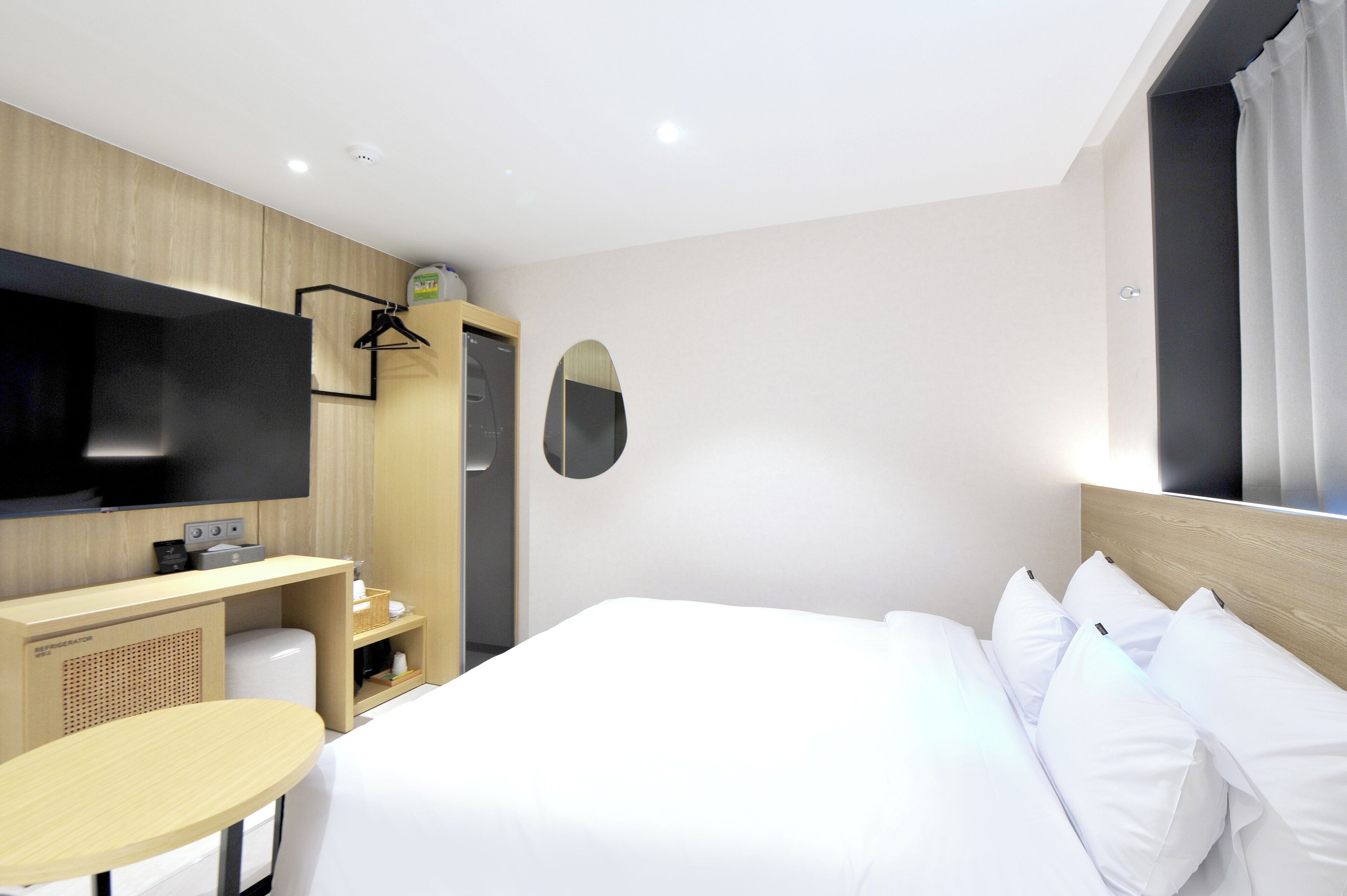 Una habitación de hotel con una cama, un escritorio, un televisor y un espejo.