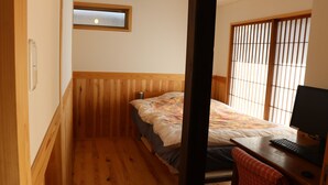 A small bedroom with a bed, a desk with a computer, and a window with vertical blinds. - Stay, Experience, Discover!! Guest House Ilonggo -Filipino-Japanese Farm House- (Tsu)