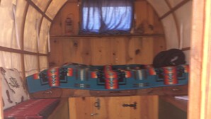 A small, enclosed cabin with a bunk bed, a window with curtains, and a patterned rug on the floor.