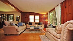 A cozy living room with wooden walls, a beige sofa, a matching armchair, and a coffee table.