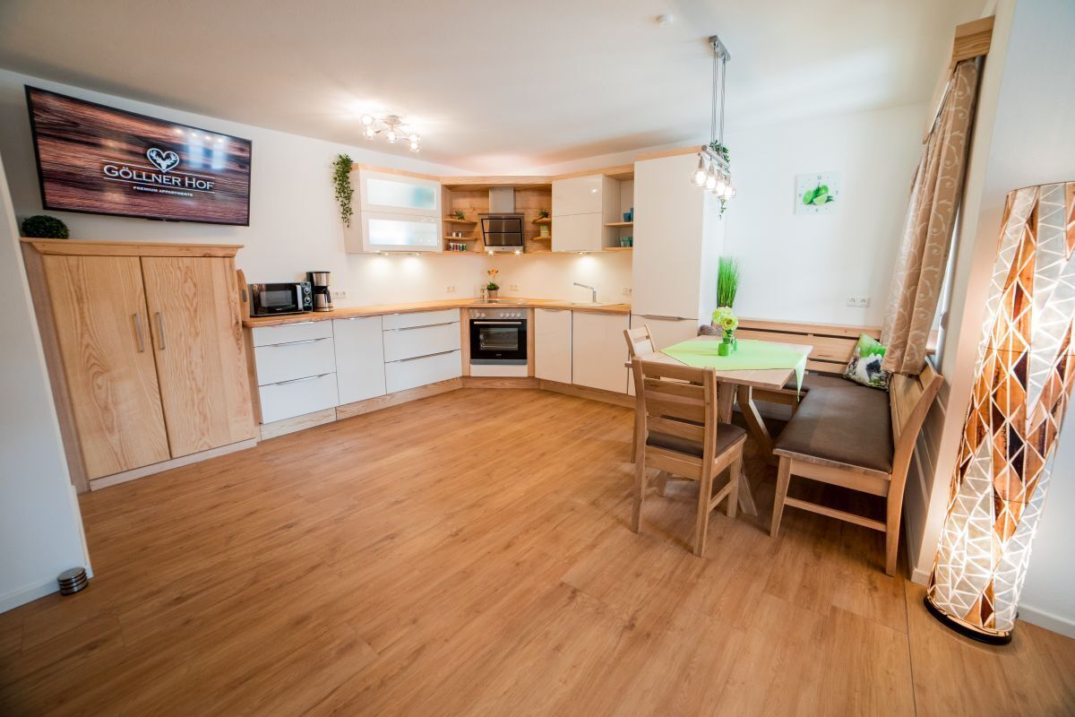 Une cuisine moderne avec des meubles en bois, un four encastré et un coin repas comprenant une table et des chaises.