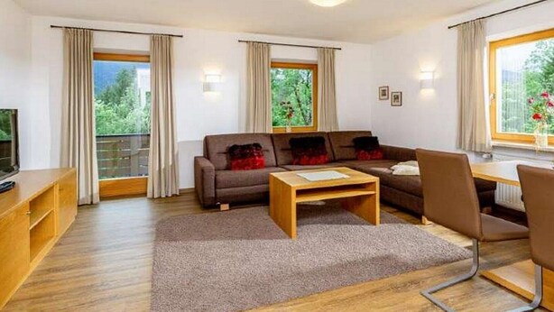 Ein modernes Wohnzimmer mit einer Couch, einem Couchtisch und einem Fernseher auf einem Holzschrank.