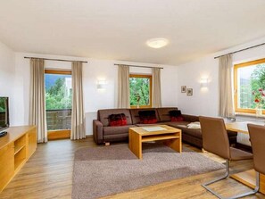 A modern living room with a sofa, coffee table, and a TV on a wooden cabinet. - At the Schutzbichler No. 3 (Reit im Winkl)