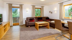Una sala de estar moderna con un sofá, una mesa de centro y un televisor sobre un mueble de madera.