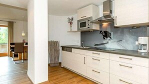 Una cocina moderna con armarios blancos, microondas y cafetera.