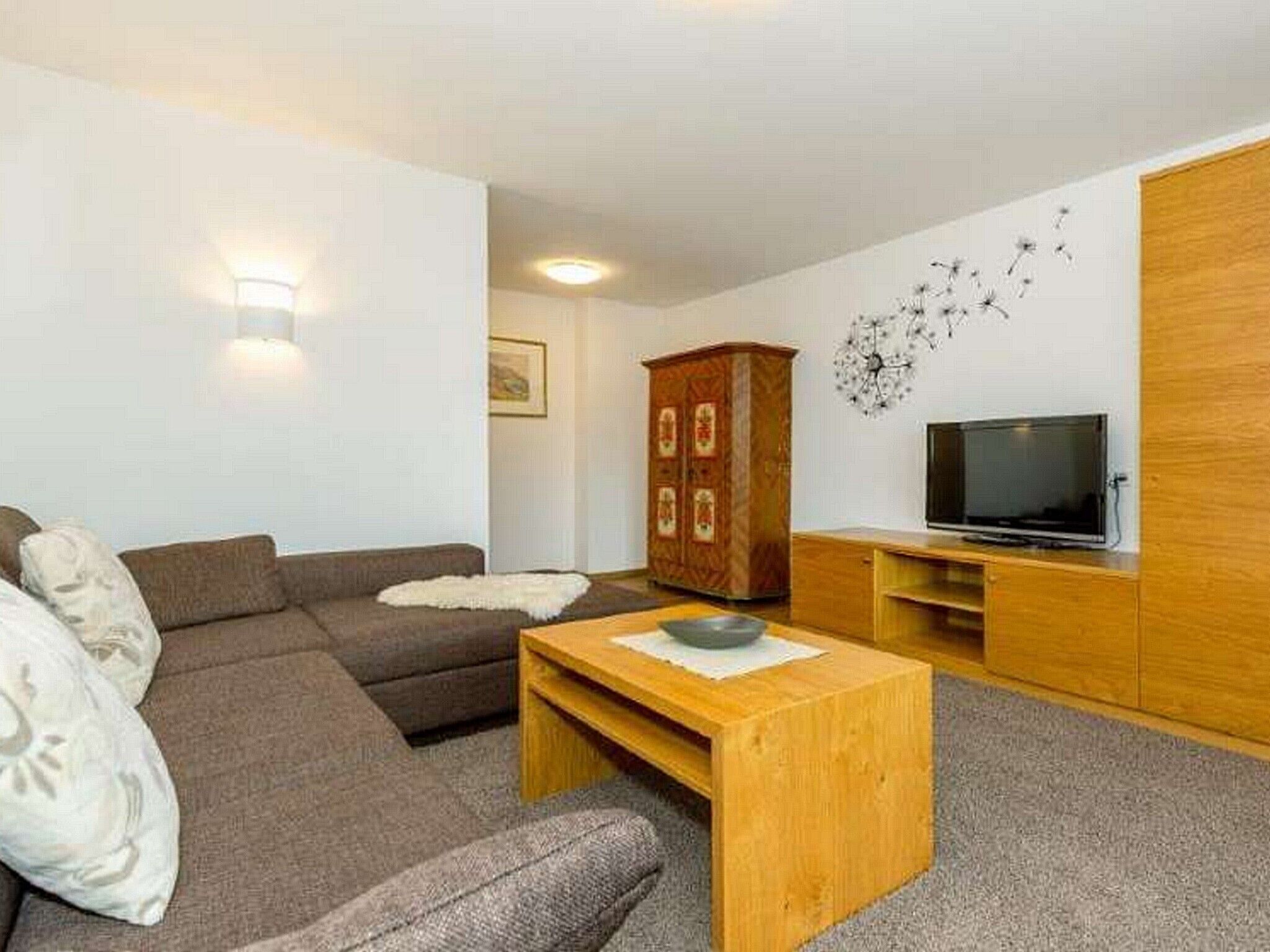 A living room with a sofa, a wooden coffee table, a TV, and a cabinet.