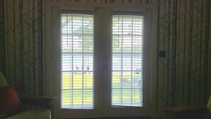 Habitació amb porta que dona a una zona exterior, amb vistes a un jardí i mobles d'exterior.