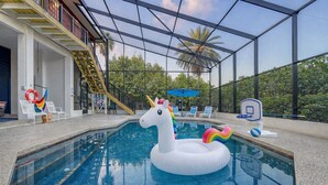 An indoor swimming pool with a unicorn float, lounge chairs, and a basketball hoop. - Ocean View of AMI | Hot Tub | IMG | 6 TVs | 2 King Beds (Bradenton)