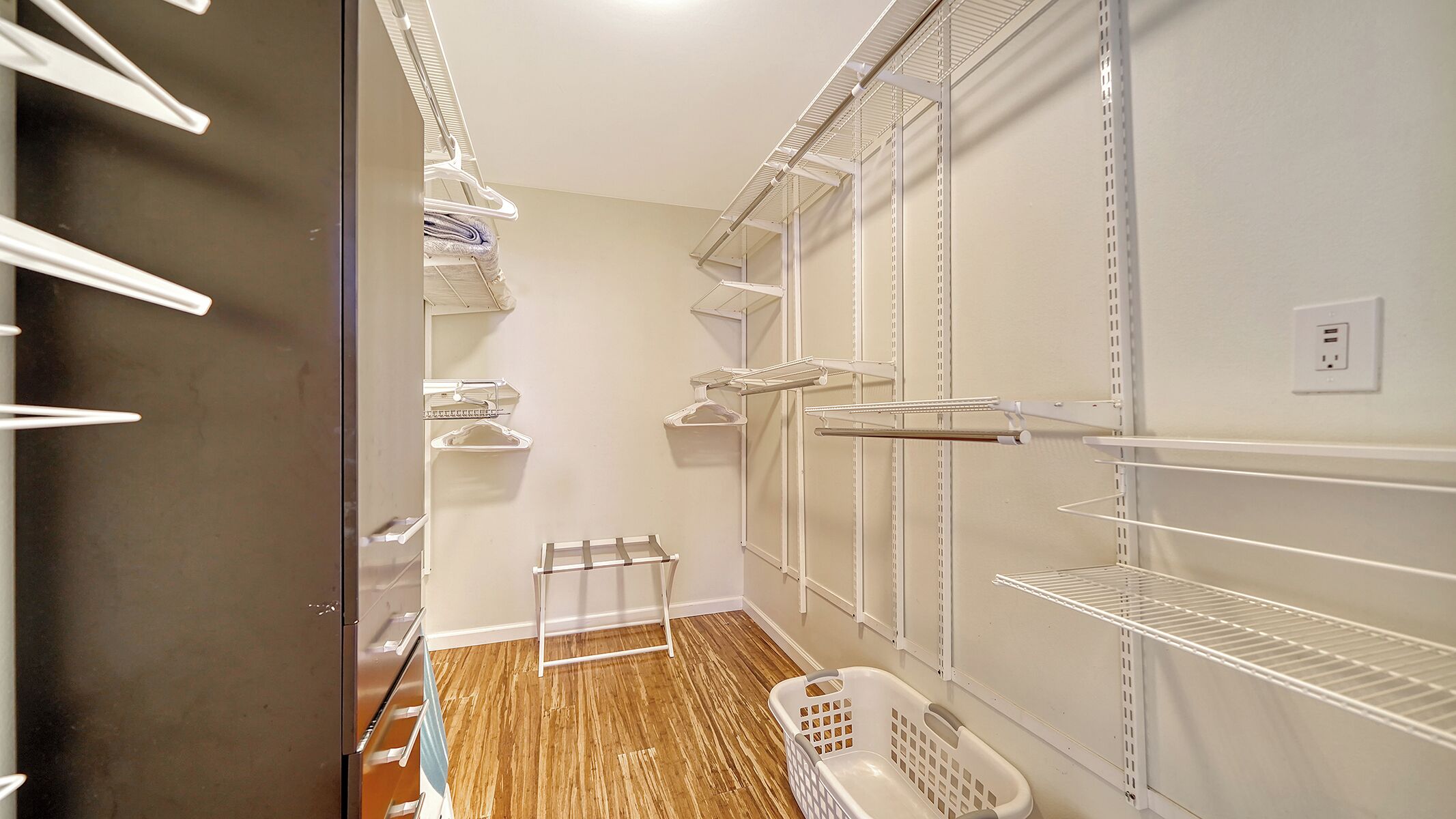 Un dressing accessible sans porte, doté d’étagères ouvertes, d’un étendoir et d’un panier à linge.