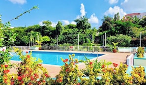 Una piscina rodeada de exuberante vegetación y una cerca blanca.