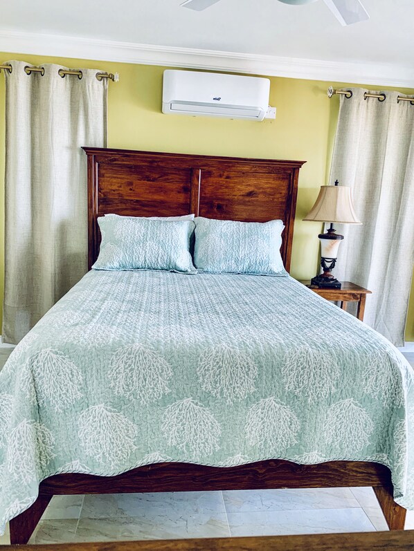 Una cama con cabecera de madera, colcha estampada azul claro y dos almohadas a juego.
