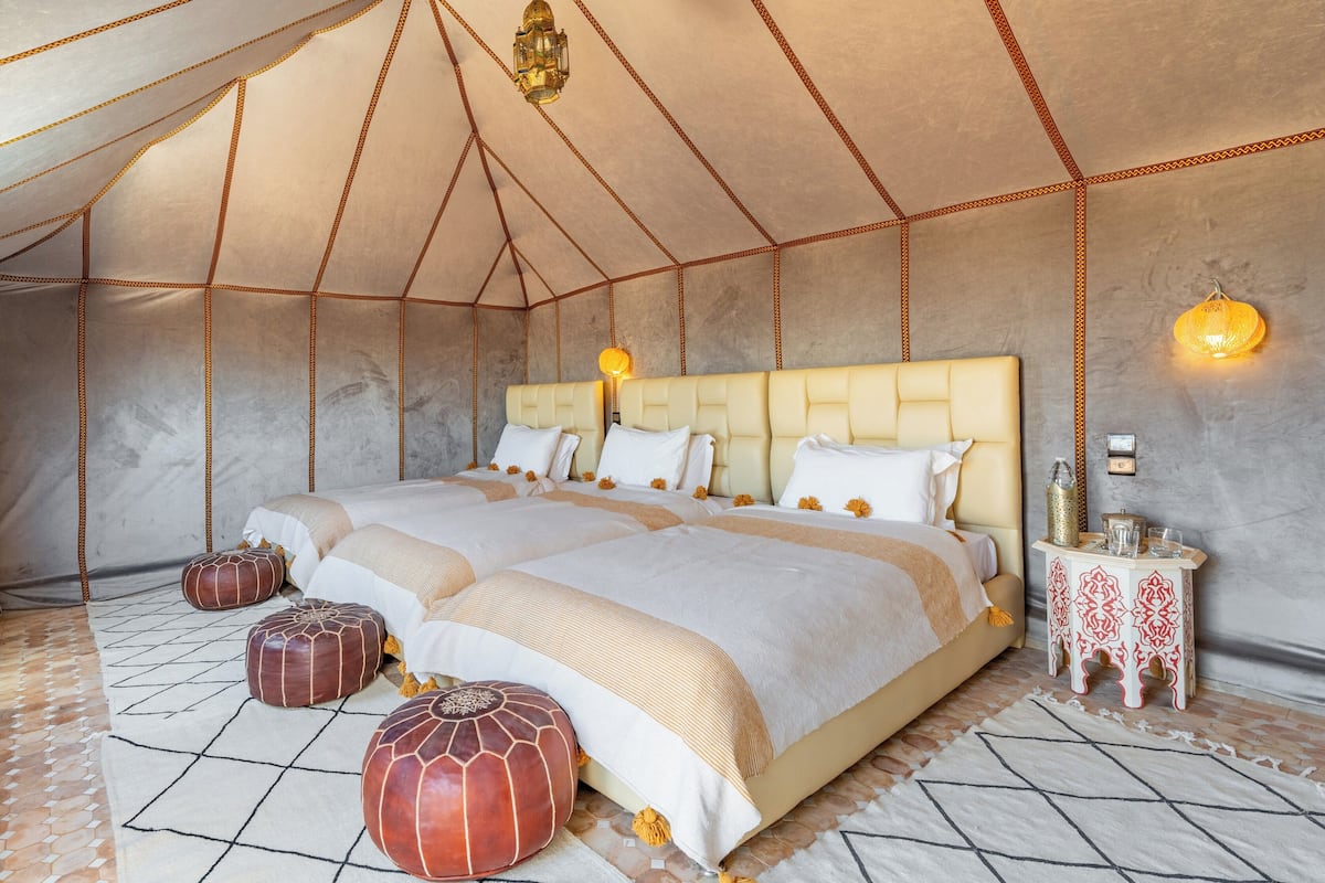 A spacious tent-style bedroom with a large bed, multiple pillows, and decorative lighting.