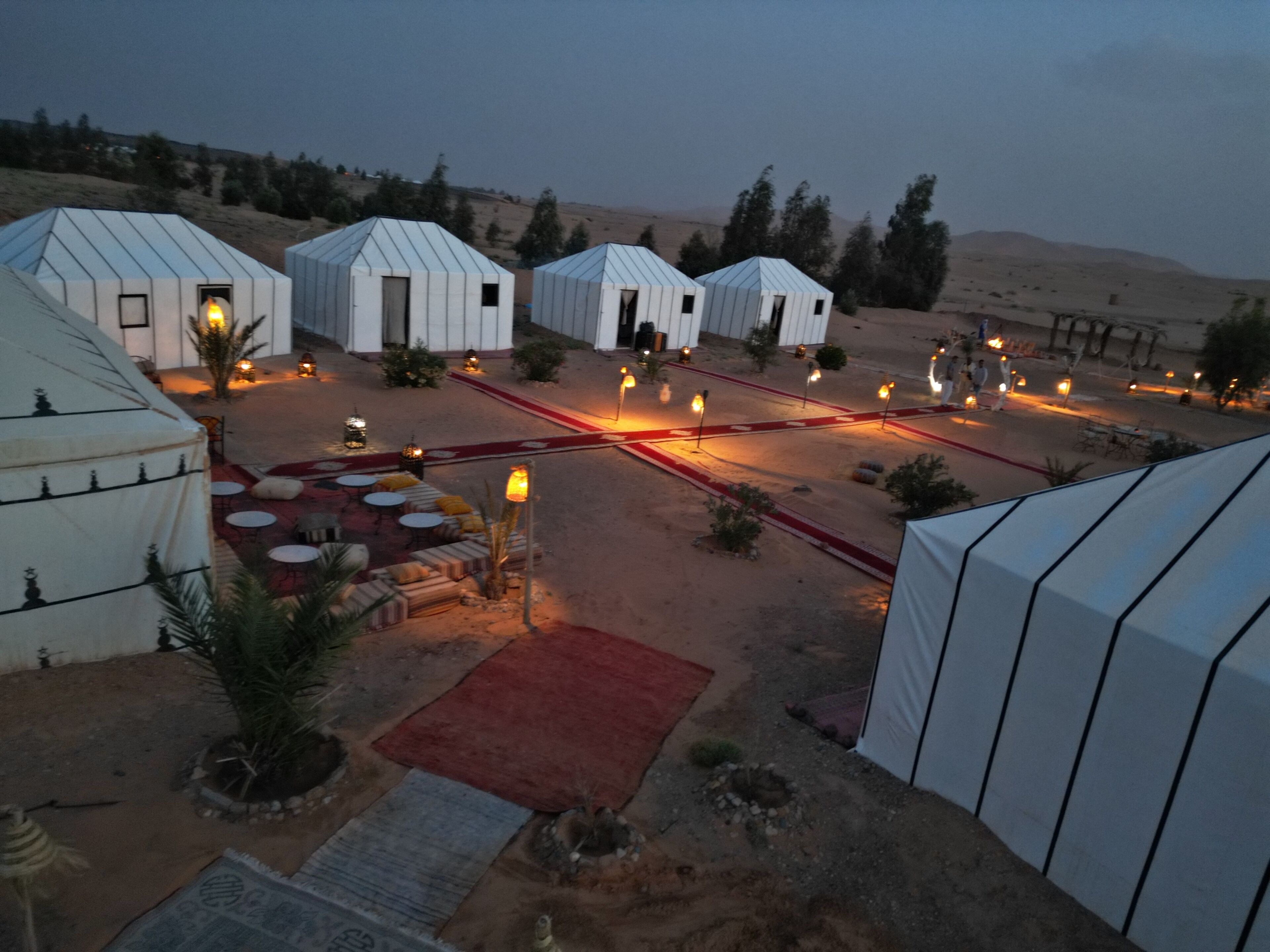 A desert resort with yurts, outdoor seating, and a red carpet pathway.