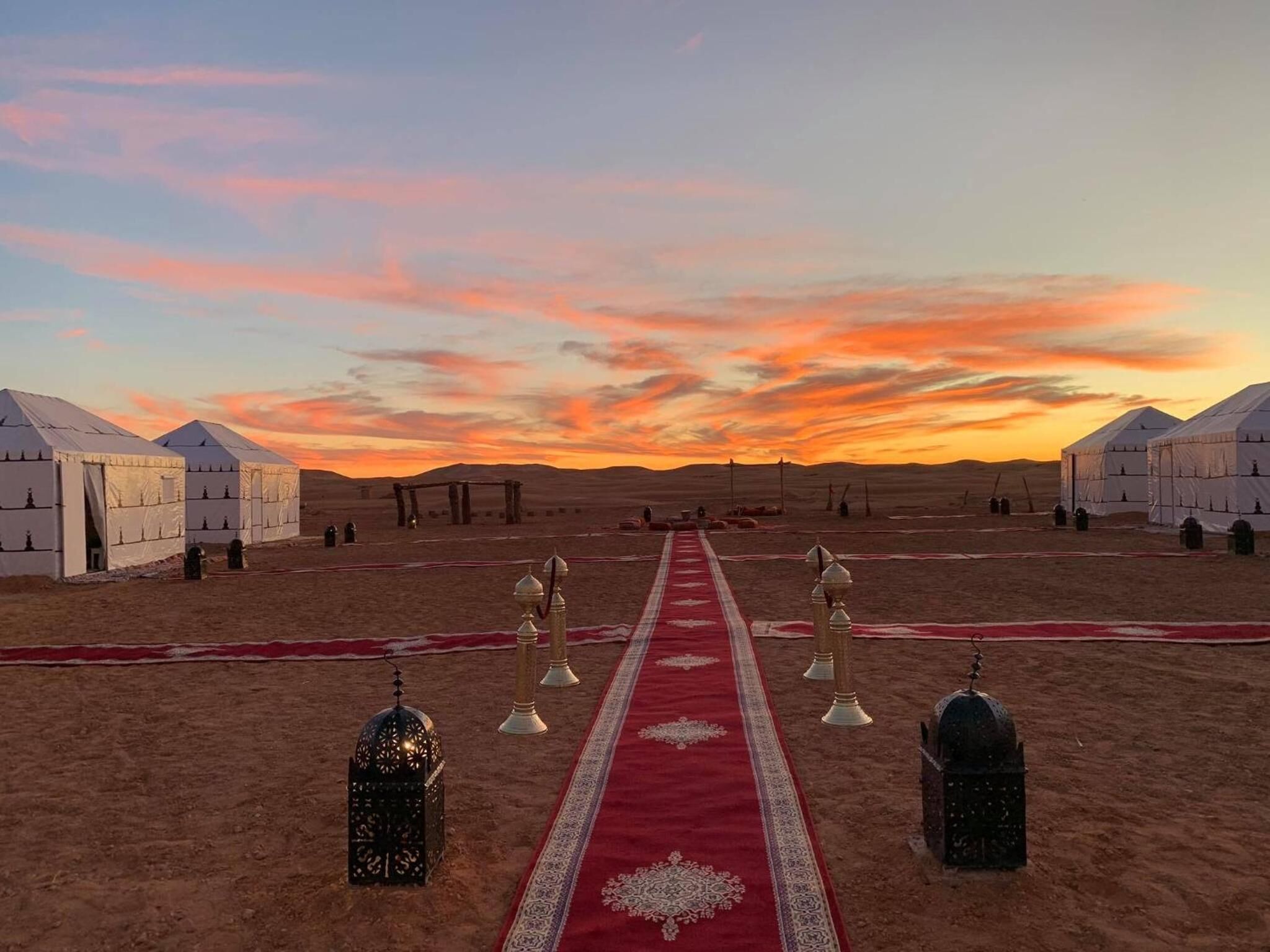 Des yourtes alignées en rangée, avec un tapis rouge menant à une structure centrale.