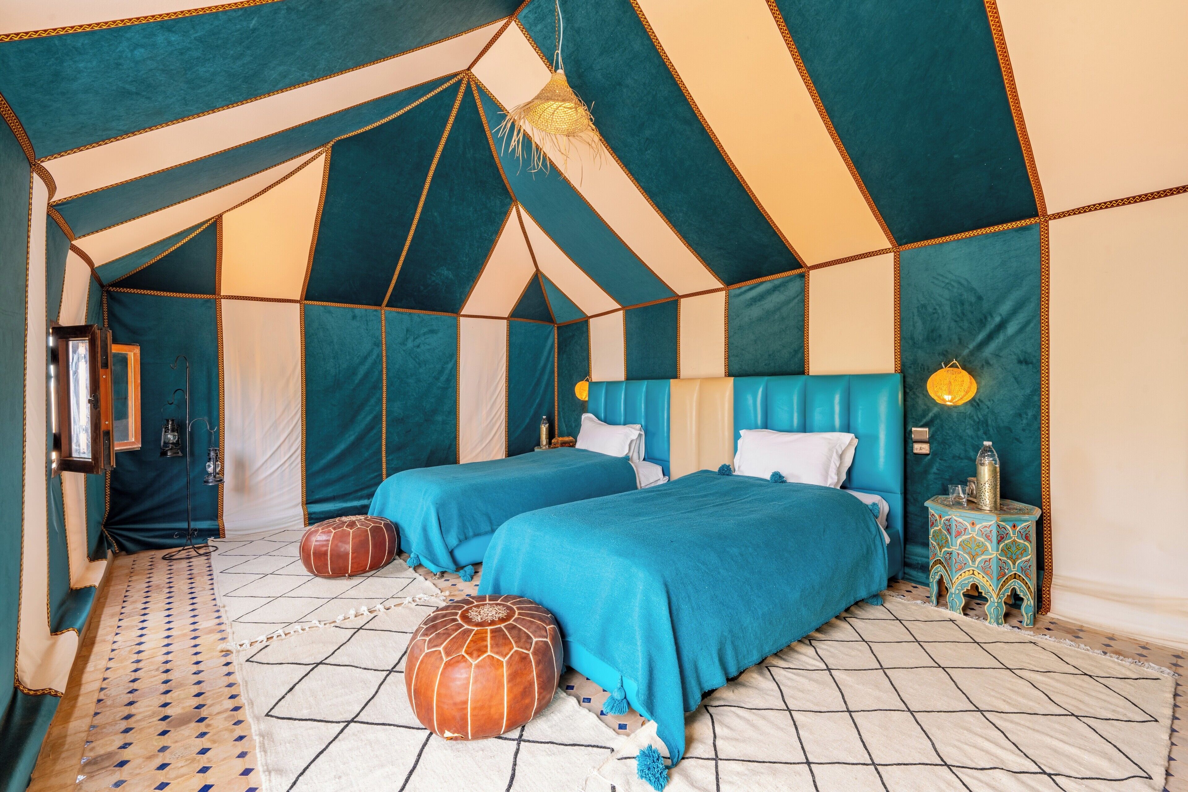 A tent-style room with two beds, a patterned rug, and a small side table.