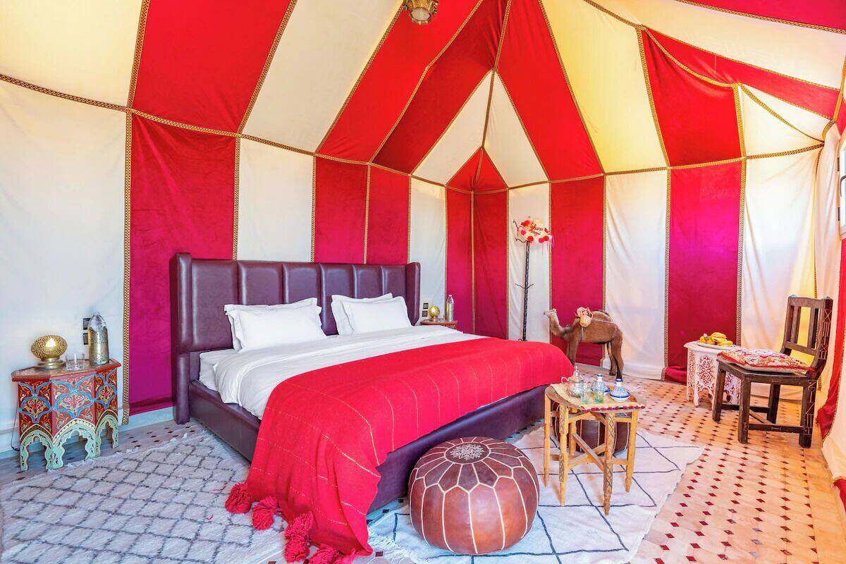 A tent-style room with a bed, a small table, a chair, and a decorative animal statue.