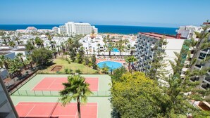 A high-rise hotel with multiple floors, a rooftop pool, tennis courts, and a view of the ocean. - 926 Precious Apartment, Beach front Sea view (Playa de las Américas)