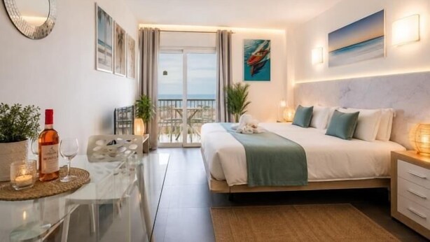 A hotel room with a bed, bedside table, lamp, and a view of the sea through the balcony doors. - 926 Precious Apartment, Beach front Sea view (Playa de las Américas)