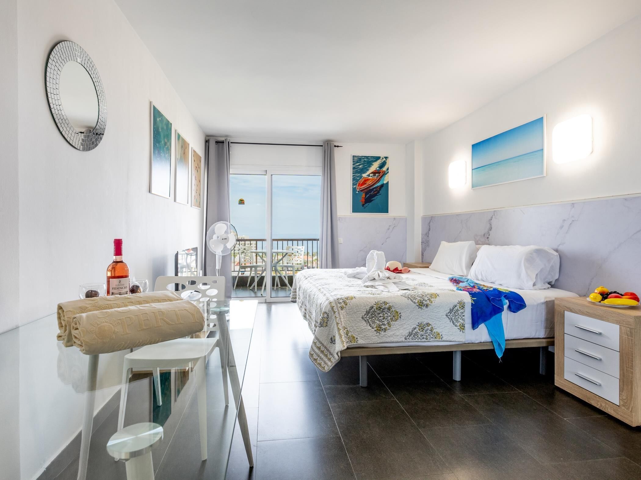 Une chambre d’hôtel moderne, équipée d’un lit, d’une table de chevet et d’un balcon avec vue.