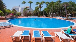 A large outdoor swimming pool surrounded by lounge chairs and palm trees. - 926 Precious Apartment, Beach front Sea view (Playa de las Américas)