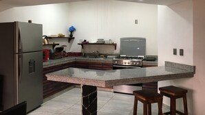 A modern kitchen with a built-in island, stainless steel appliances, and wooden accents. - PALMAS DE CHAHUE 8 (1,100 SF) (Bahías de HUATULCO)