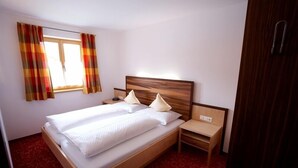 Une chambre d’hôtel avec un lit en bois, deux tables de chevet et une fenêtre avec des rideaux.