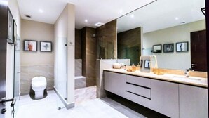 A modern bathroom with a large mirror, a toilet, and a shower area.