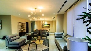 A modern living room with a sofa, armchairs, a coffee table, and a dining area with chairs and a table.