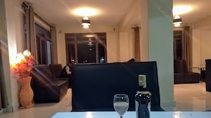A dining area with a table set for two, featuring a menu, a wine glass, and a salt and pepper shaker. - Lantana Comfy (Kakamega)