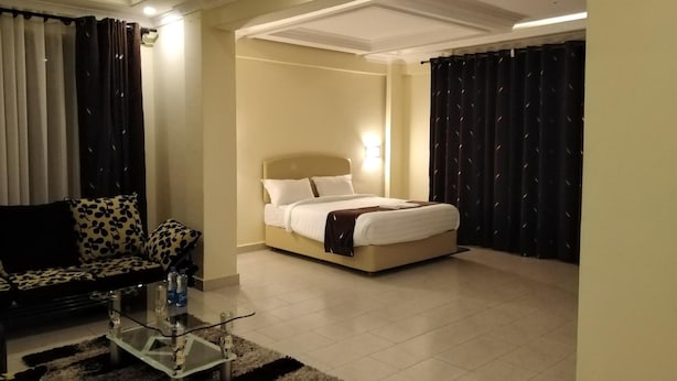 A modern hotel room with a bed, a sofa, and a glass coffee table. - Lantana Comfy (Kakamega)