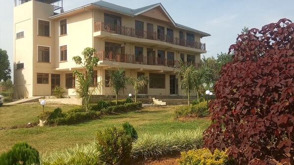 A multi-story building with balconies, a well-maintained lawn, and various plants.
