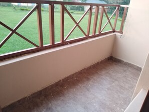 A balcony with a wooden railing and a view of a green lawn.