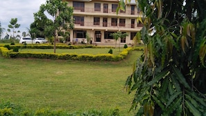 A multi-story hotel with a well-maintained lawn and a white car parked in front. - Lantana Comfy (Kakamega)