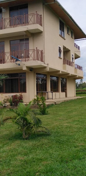 A multi-story building with balconies, large windows, and a well-maintained lawn.