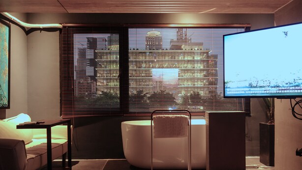 A modern bathroom with a bathtub, a large mirror, and a television. - PInHouse (Kaohsiung)