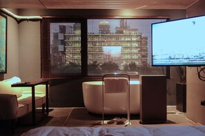 Un baño moderno con bañera, un espejo grande y un televisor.