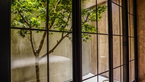A traditional Japanese room with tatami flooring, a low wooden table, and a view of a tree through a shoji screen. - PInHouse (Kaohsiung)