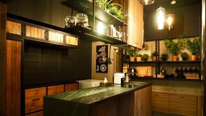 A modern kitchen with wooden cabinets, a marble island, and potted plants. - PInHouse (Kaohsiung)
