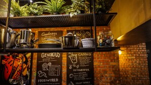 A kitchen area with stainless steel pots, a coffee machine, and a shelf with potted plants. There are chalkboard signs with words like "Generous," "Caring," and "Delightful." - PInHouse (Kaohsiung)