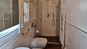 Et lille badeværelse med badekar, toilet og bruser.