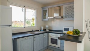 Una cocina moderna con horno empotrado, microondas y cafetera. Cuenta con ventana que proporciona luz natural y vistas al exterior.