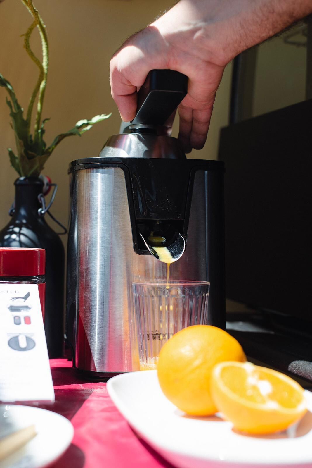 A hand pouring a drink from a metallic shaker into a glass.