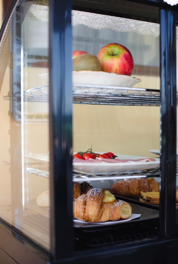 Une vitrine contenant des pâtisseries, des fruits et une assiette de nourriture.