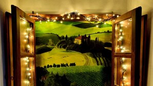 Een schilderij van een landelijk landschap, zichtbaar door een open raam met lichtslingers.