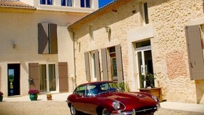 Un immeuble de deux étages devant lequel est garée une voiture rouge.