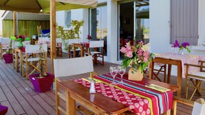 Un espace de restauration en plein air, avec des tables et des chaises en bois, protégé par une grande auge.