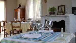 Une salle à manger avec une table dressée pour quatre personnes, agrémentée d’une nappe à rayures, de verres à vin et de couverts.