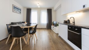 Eine moderne Küche mit Essbereich, inklusive Holztisch, schwarzer Stühle und eingebautem Ofen.