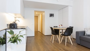 Eine moderne Küche mit Einbauherd, einer Essecke mit Tisch und Stühlen sowie einem grauen Sofa.