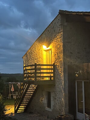 Un bâtiment en pierre avec un escalier en bois menant à un balcon.